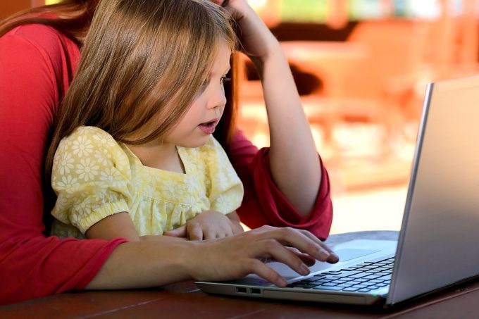 Parent and child looking at computer screen, limiting screen time